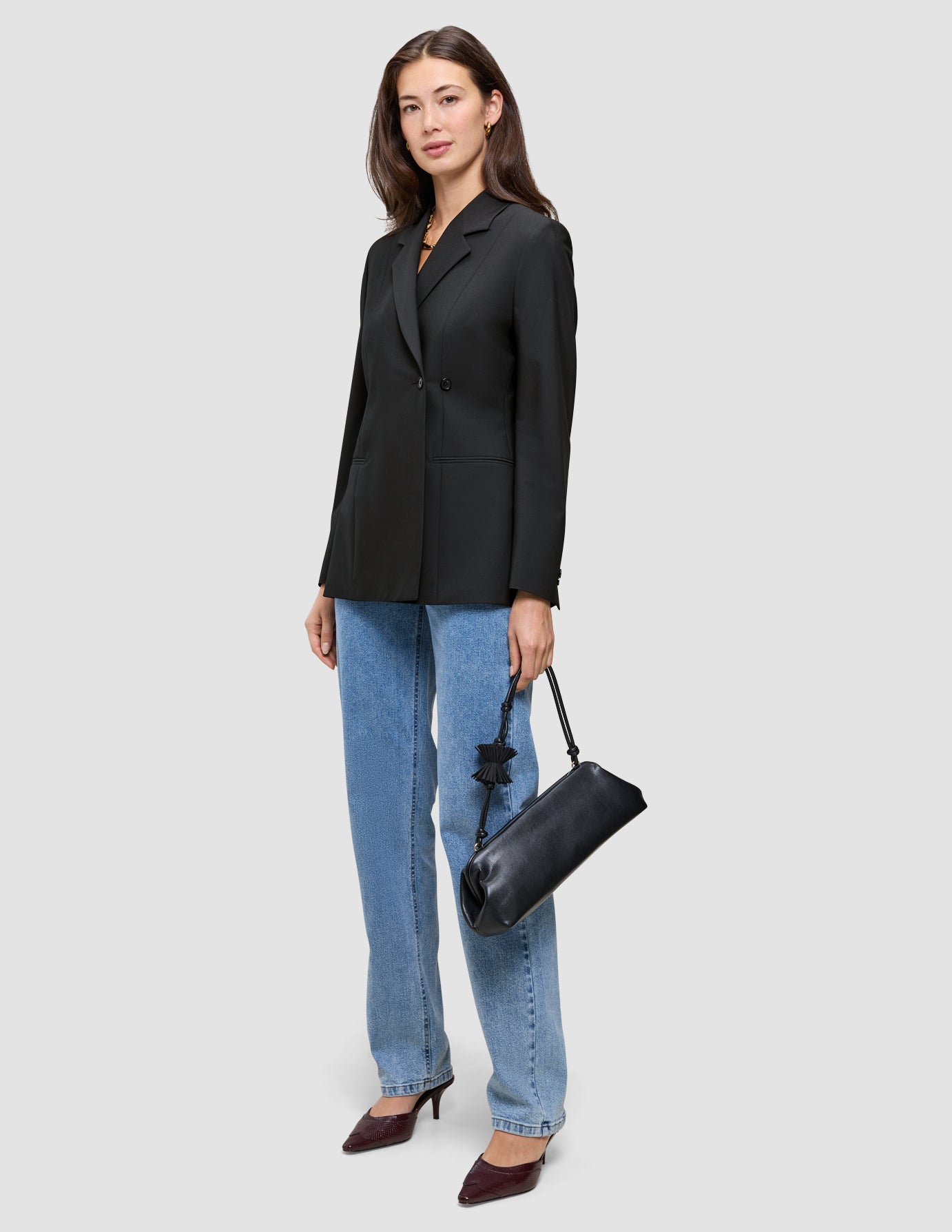 En kvinne kledd i en svart Women’s Avira Blazer og blå jeans, med en svart skulderveske.